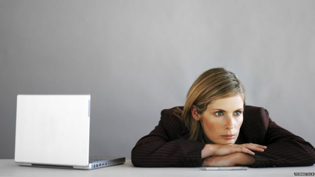 Woman at desk, looking bored