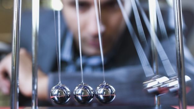 Businessman looks at Newton's cradle