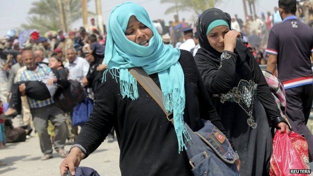 Displaced Sunni women fleeing the violence in Ramadi, carry bags as they walk on the outskirts of Baghdad, 24 May 2015