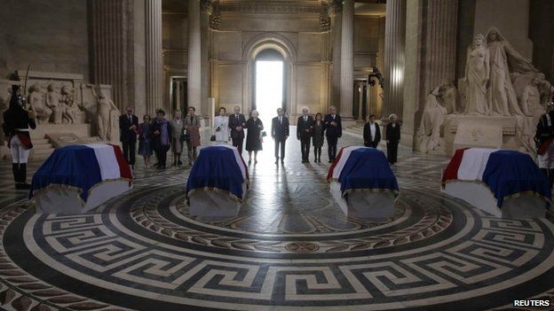 French President Francois Hollande (C) stands with family members as they pay their respects in front of four flag-draped caskets inside the Pantheon during a ceremony in Paris, France, May 27, 2015