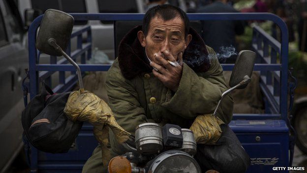 A Chinese labourer smokes a cigarette at a local market 26 September 2014