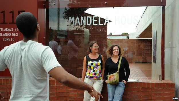 Tourists pose for a photo in front of the Mandela House, Nelson Mandela's former house, in Soweto on March 29, 2013.