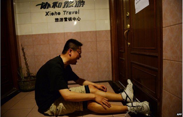 A relative of missing passengers who were on a ship which sank in the powerful Yangtze river the night before reacts after hearing news of the sinking outside a travel agency in Shanghai on 2 June 2015