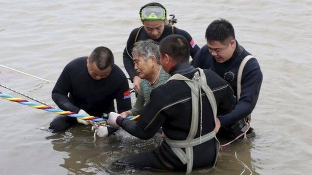 A woman is helped after being pulled out by divers from a sunken ship in Jianli, Hubei province, China, 2 June 2015.