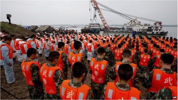Rescuers bow during a commemoration service near the raised ship Eastern Star on the Yangtze River in Jianli county.
