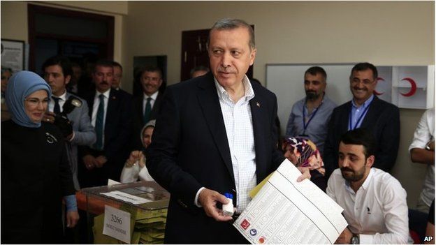 Turkey’s President Recep Tayyip Erdogan, accompanied by his wife Emine, left, holds his ballot as he prepares to vote at a polling station in Istanbul.