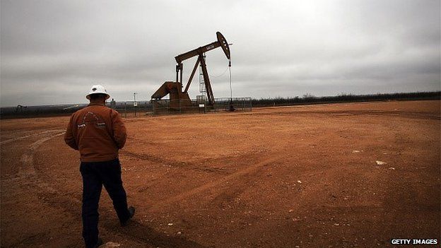 A member of staff approaching a nodding donkey extracting oil in Texas.