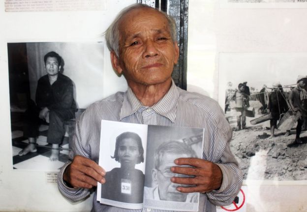 Bou Meng with a picture of his wife in a book