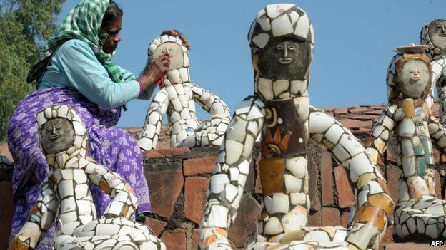 This photo taken on October 31, 2014 shows an Indian worker cleaning sculptures in the Rock Garden, built by self-taught Indian artist Nek Chand Saini over the course of 18 years, in Chandigarh.