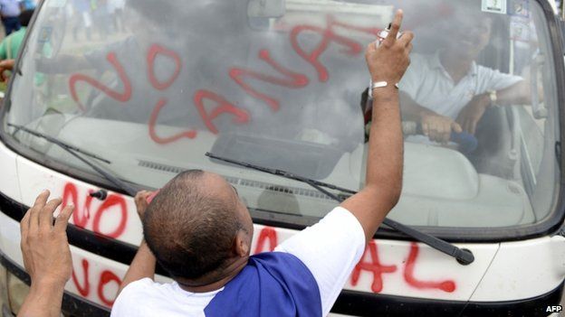 A man sprays graffiti on a vehicle during a demo against a planned canal in Nicaragua