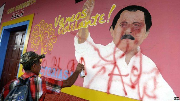 A man sprays graffiti on a mural during a demo against a planned canal in Nicaragua