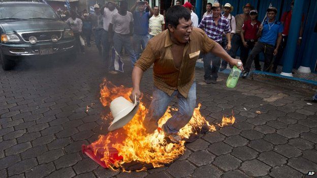 A protester burns a flag of Nicaragua's ruling party during a rally against a planned canal