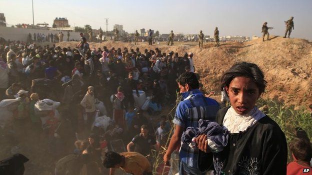 Syrian refugees are watched by Turkish troops after breaking through the border fence near Tal Abyad (14 June 2015)