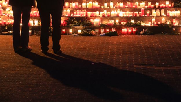 Pupils stand in front of candles and flowers that have been left outside the Joseph-Koenig college in Haltern am See, Germany, 24 March 2015.