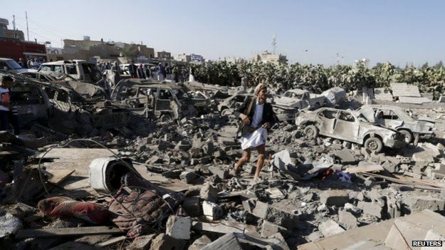 An armed man walks on the rubble of houses destroyed by an air strike near Sanaa Airport (26 March 2015)