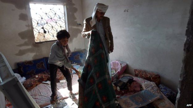 Yemeni man and boy clear up inside their home after Saudi-led coalition air strike in Sanaa (26 March 2015)