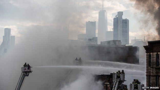 New York City Fire Department staff work to extinguish a fire as a building burns after an explosion