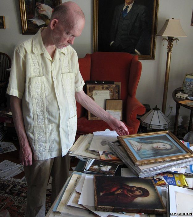 Mark Landis at home with some of his pictures