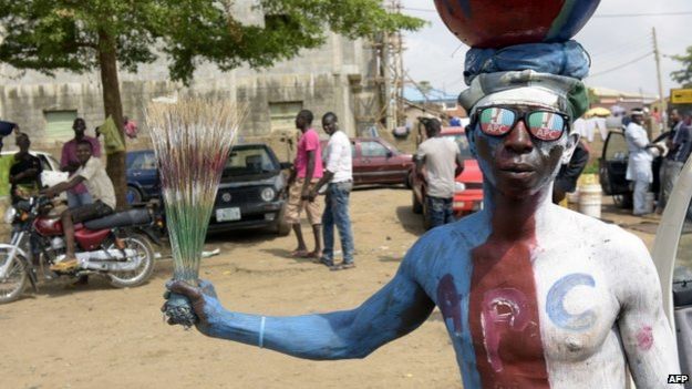 A man wears glasses and body paint adorned with the logo of Nigeria's main opposition All Progressives Congress (APC) as residents await results of the presidential election in Abuja