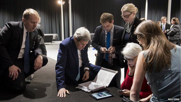 US Secretary of State John Kerry and staff watch a tablet in Lausanne as President Barack Obama makes a state address on the status of the Iran nuclear program talks on 2 April, 2015