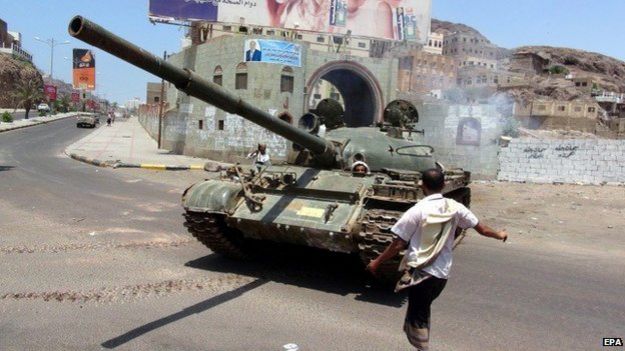 A man stands beside a tank manned by pro-government militia in Aden