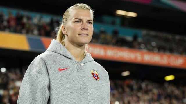 Ada Hegerberg walks on the pitch in a grey hoody and blonde hair tied in a ponytail