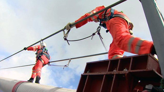 People in safety harnesses inspect the Forth Road Bridge