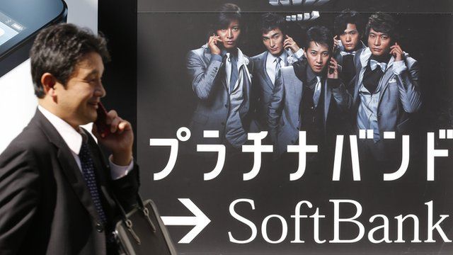 A man walks past a Softbank advertisement board in Tokyo