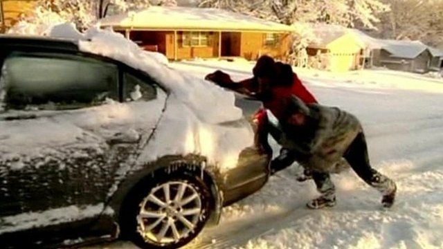 People pushing car in snow