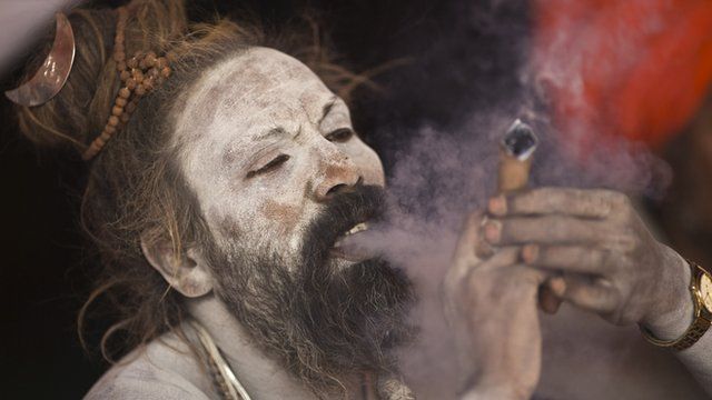 A Sadhu smokes marijuana on the banks of river Ganges