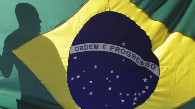 The shadow of a demonstrator is cast on a Brazilian flag