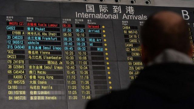Man stands under arrivals board showing flight information