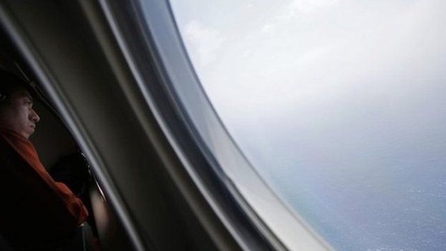 A Japanese Coast Guard officer looks out the window of a plane during the search for flight MH370