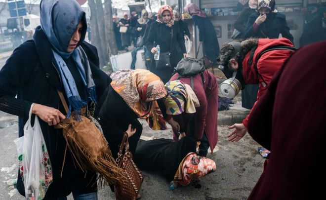 Women helps another woman who felt as Turkish anti-riot police officers use tear gas to disperse supporters in front of the headquarters of the Turkish daily newspaper Zaman in Istanbul on March 5, 2016