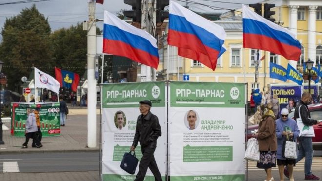 Local residents walk by canvassing posters of the democratic opposition in downtown Kostroma (10 September 2015)