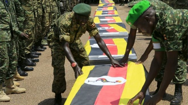 Uganda army soldiers lay national flags on the caskets carrying the remains of Ugandan soldiers who were killed in Somalia this week, at a military airbase in Entebbe on 3 September 2015