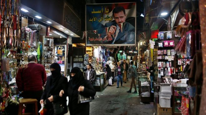 A poster of the Syrian President Bashar Assad that reads "Assad we are with you for ever" in Arabic hangs at the popular Hamidiyeh old market in Damascus