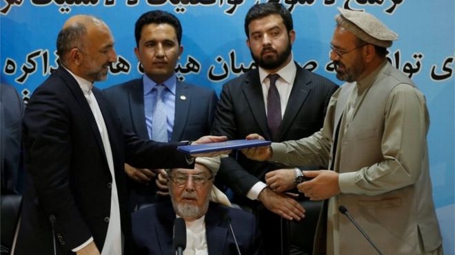 Mohammad Amin Karim (R), representative of Gulbuddin Hekmatyar, and Afghanistan national security adviser Mohammad Hanif Atmar (L) hold a document after signing a peace deal in Kabul, Afghanistan, September 22, 2016.