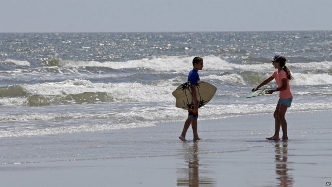 Two children walk with their skim boards on the beach in Oak Island, North Carolina - 15 June 2015