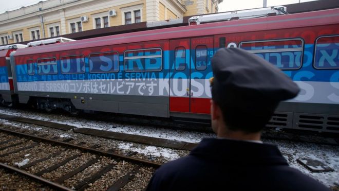 A railroad worker stands by the first train decorated with letters that read "Kosovo is Serbian" written in twenty languages