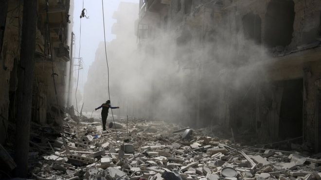 A man walks on the rubble of damaged buildings after an air strike on the rebel held Qaterji district of Aleppo, Syria (25 September 2016)