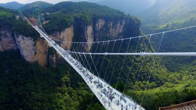 Visitors walk across a glass-floor suspension bridge in Zhangjiajie in southern China's Hunan Province Saturday, Aug. 20, 2016