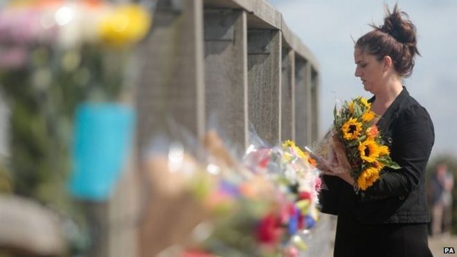 A woman lays flowers on the Shoreham Tollbridge near the site where a Hawker Hunter fighter jet plummeted on to the A27