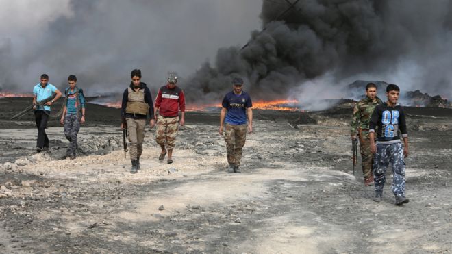 صور لبعض الاحداث المهمة التي وقعت عام 2016 _93125567_iraq_1611_qayyara_tribalfighterswalkasfireandsmokerisesfromoilwellssetablazebyislamicstatemilitantsbeforeism