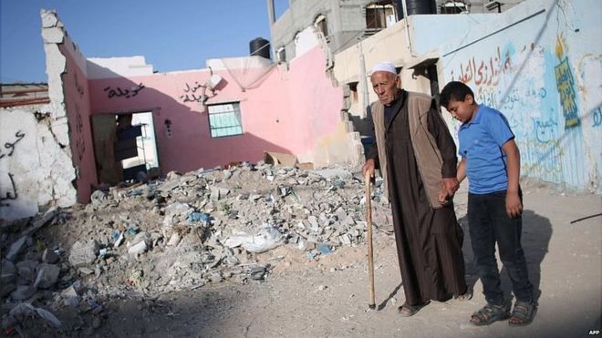Palestinians walk past rubble from 2014 war in Gaza