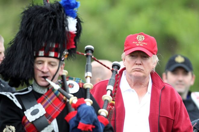 Donald Trump next to a man playing bagpipes at the opening of The Trump International Golf Links Course in July 2012