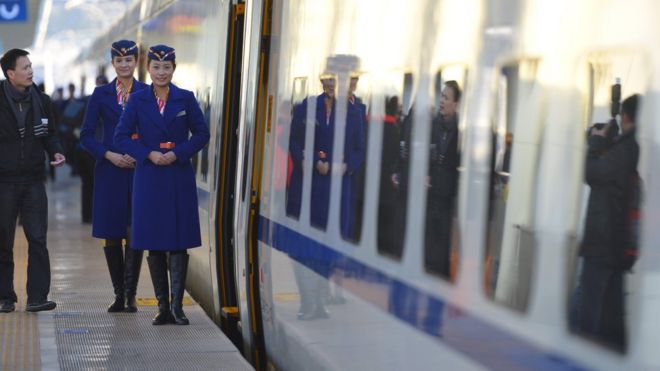 Train conductors stand outside the cabin of a bullet train in China