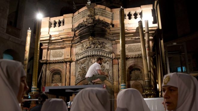 Christian nuns watch as a team of experts begin renovation of Jesus" tomb