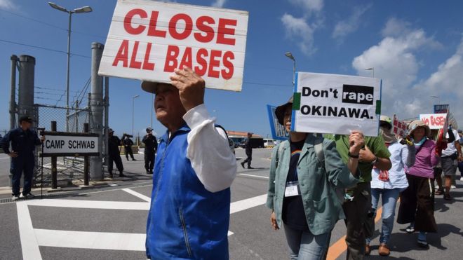 People hold placards as they protest against the presence of US bases on Okinawa prefecture on 17 June