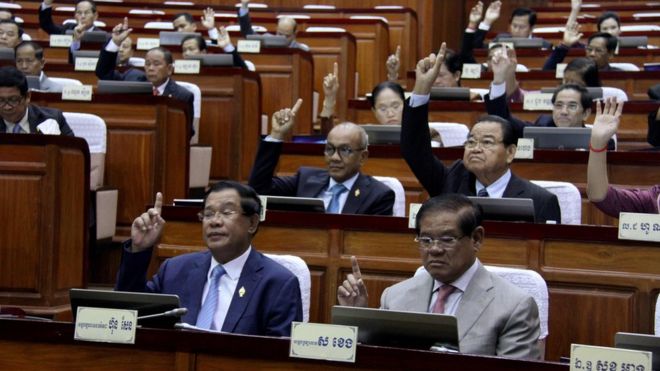 This handout taken and released on February 20, 2017 by the Cambodia National Assembly shows Cambodia"s Prime Minister Hun Sen (front L) and other lawmakers voting during the parliament meeting at the National Assembly building in Phnom Penh. They have their right hands raise in the air.
